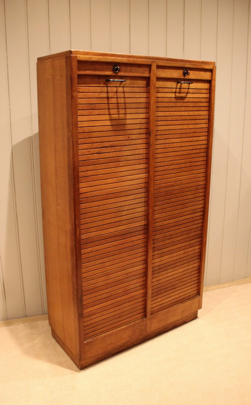 A tall French oak filing cabinet featuring twin vertical tambour slatted doors with metal handles and keyholes.