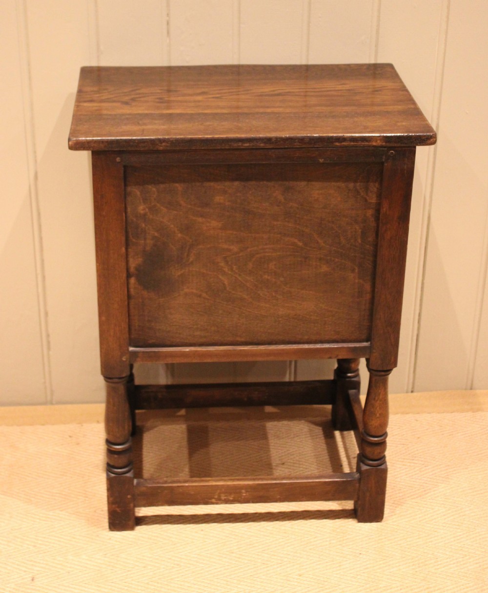 A small dark oak side cabinet featuring double carved panel doors, iron hinges, turned legs, and lower wooden stretchers. View XIII