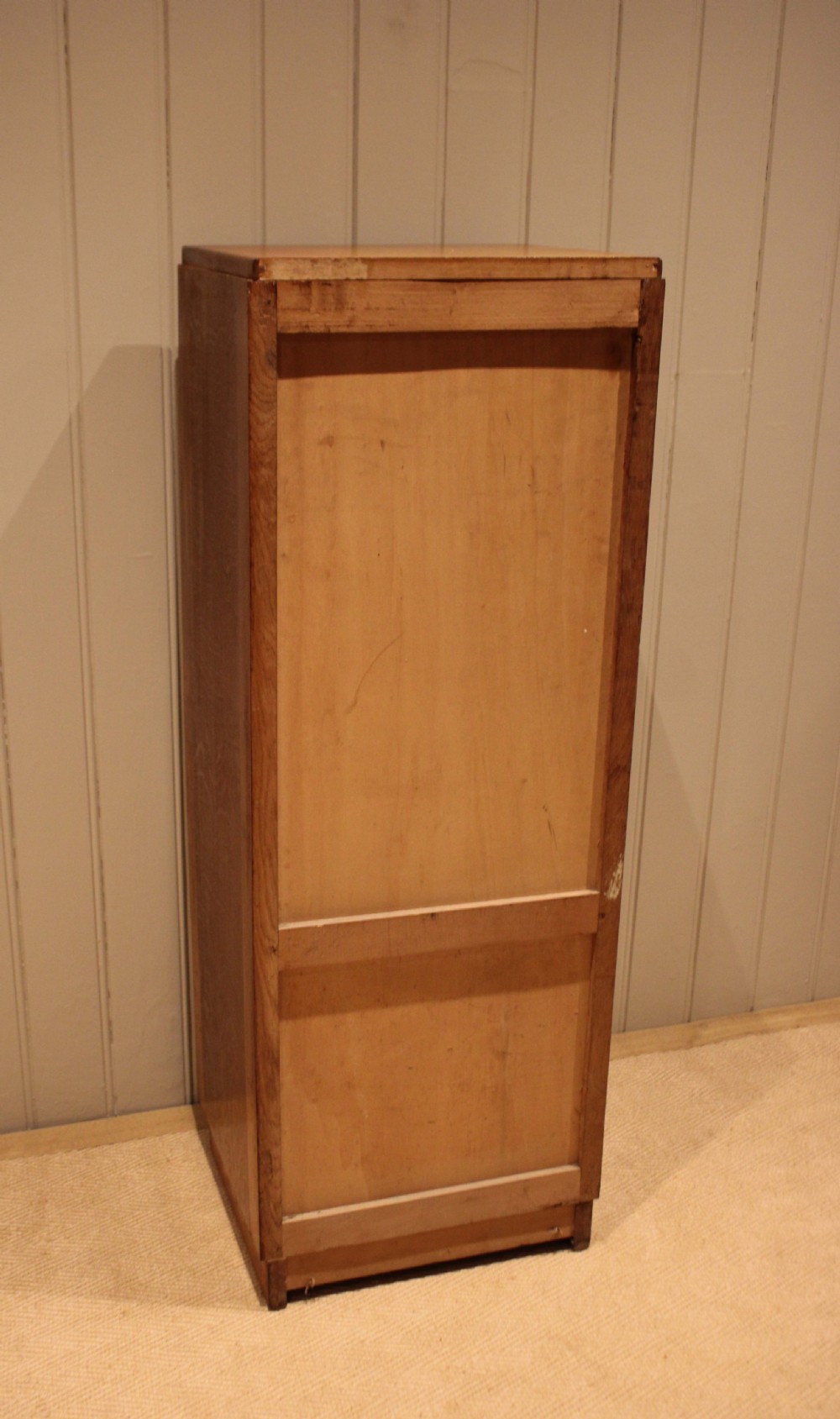 A tall, narrow antique oak filing cabinet with a vertical slatted tambour shutter front, top metal pull handle, and keyhole lock. View XI