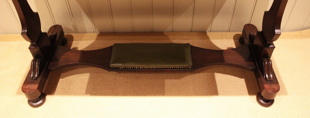 A mahogany writing table featuring a green gilt-tooled leather inset writing surface, a three-sided gallery rail, two drawers with brass ring pull handles, and a trestle base with a central footrest. View XIII