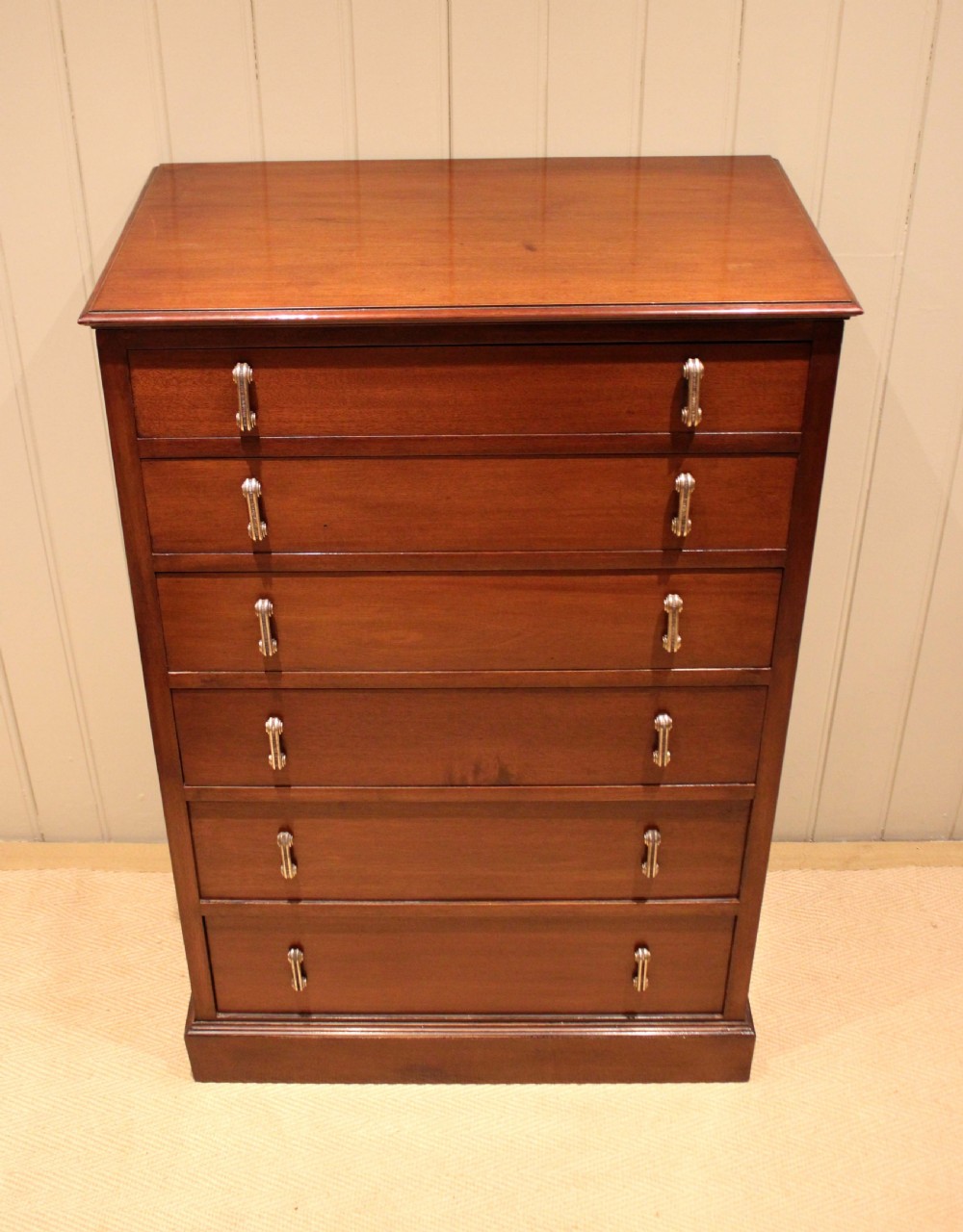 A tall mahogany chest of drawers featuring six horizontal drawers with vertical metal drop handles on a plinth base. View II