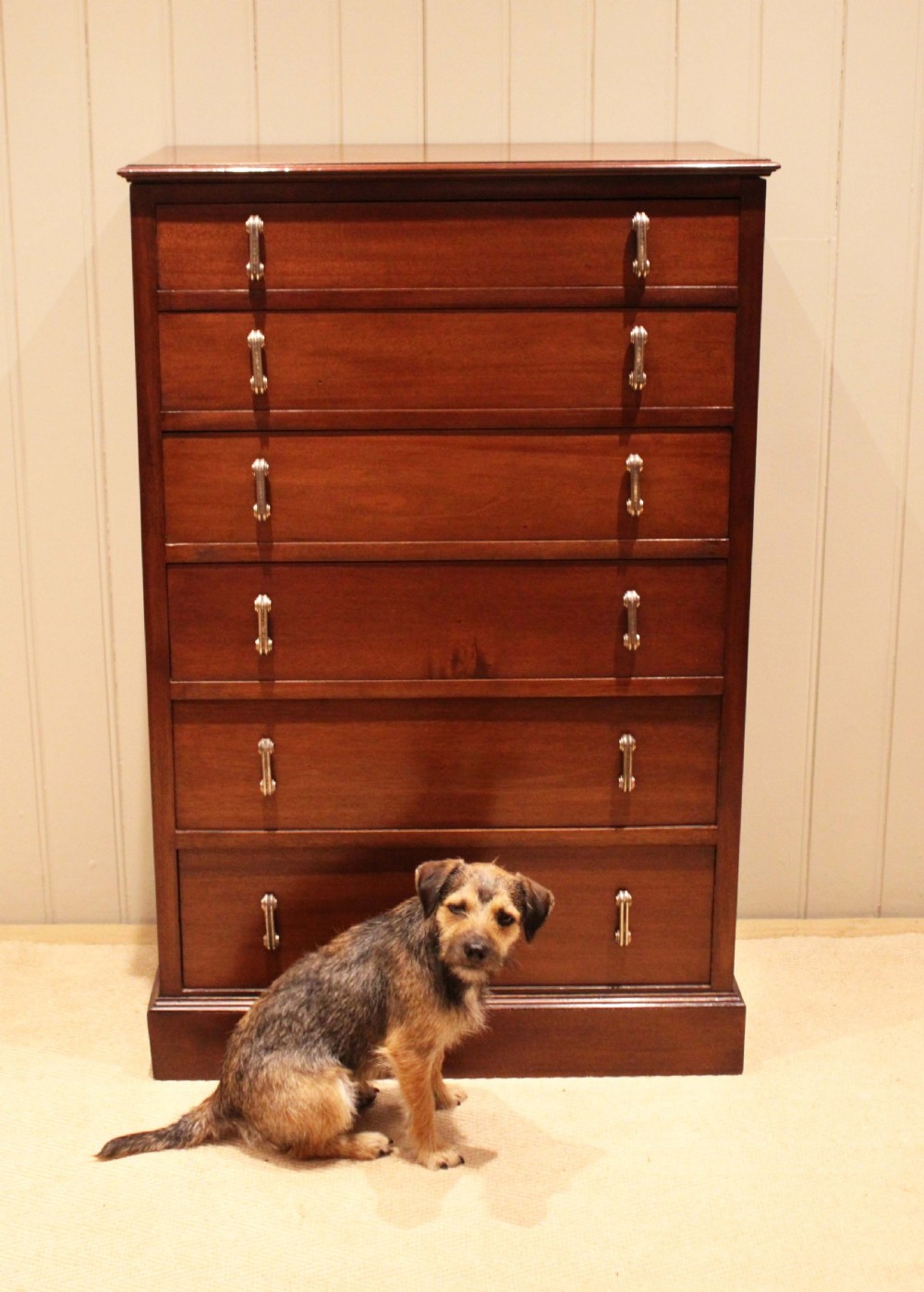 A tall mahogany chest of drawers featuring six horizontal drawers with vertical metal drop handles on a plinth base. View V