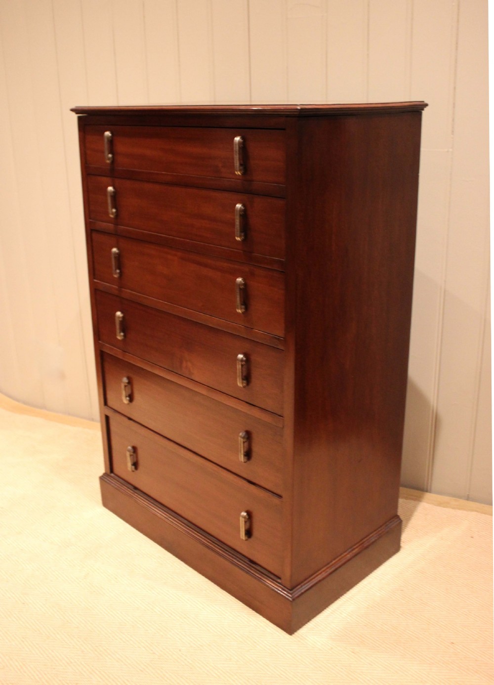 A tall mahogany chest of drawers featuring six horizontal drawers with vertical metal drop handles on a plinth base. View IX