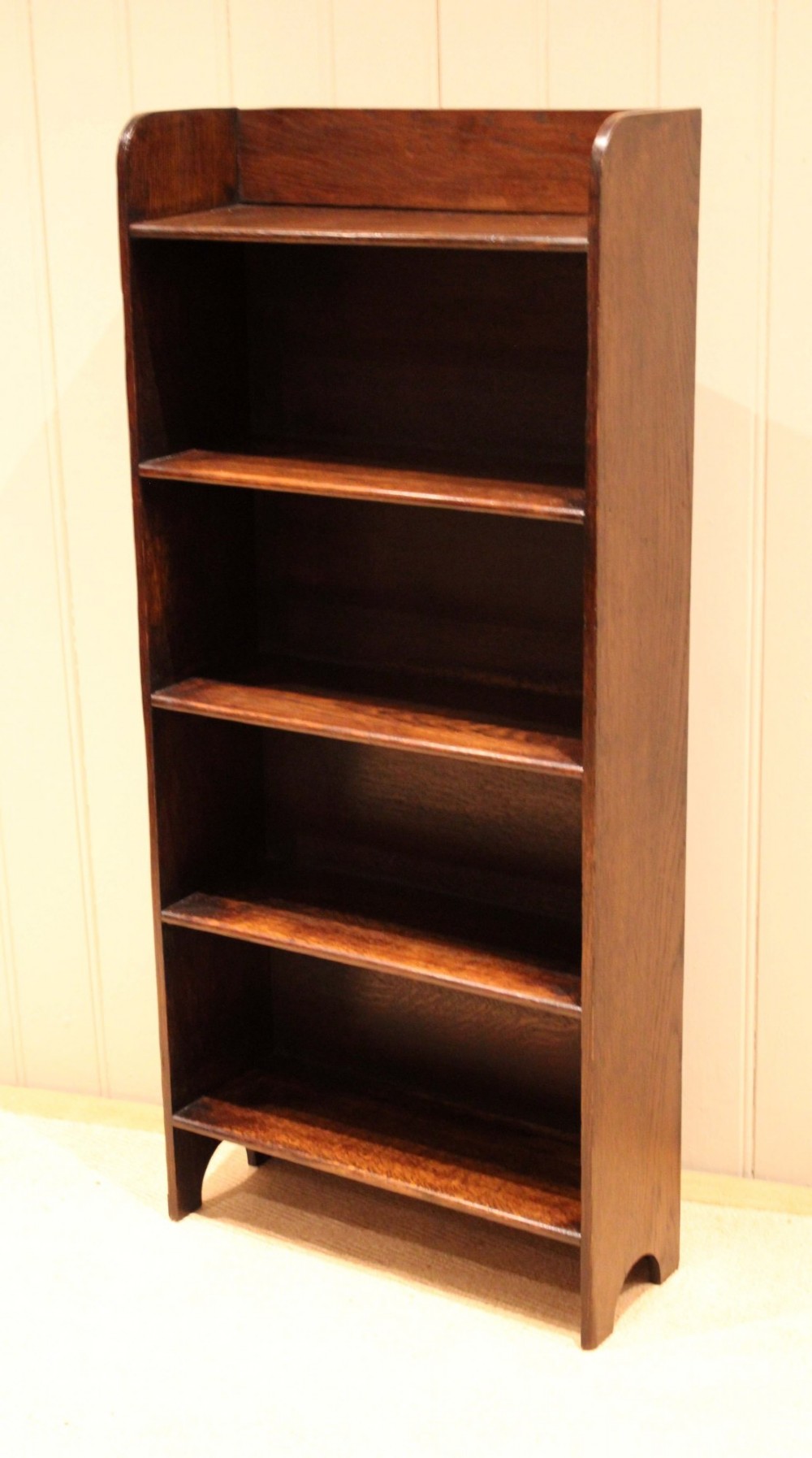A tall dark oak open bookcase with four fixed shelves and shaped side profile cut-outs at the base. View II