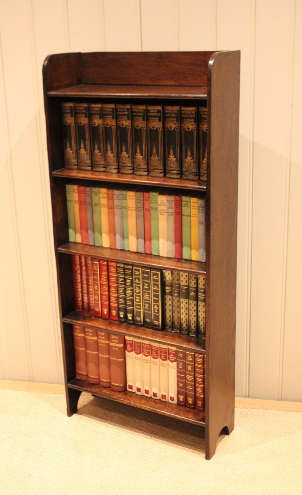 A tall dark oak open bookcase with four fixed shelves and shaped side profile cut-outs at the base. View V
