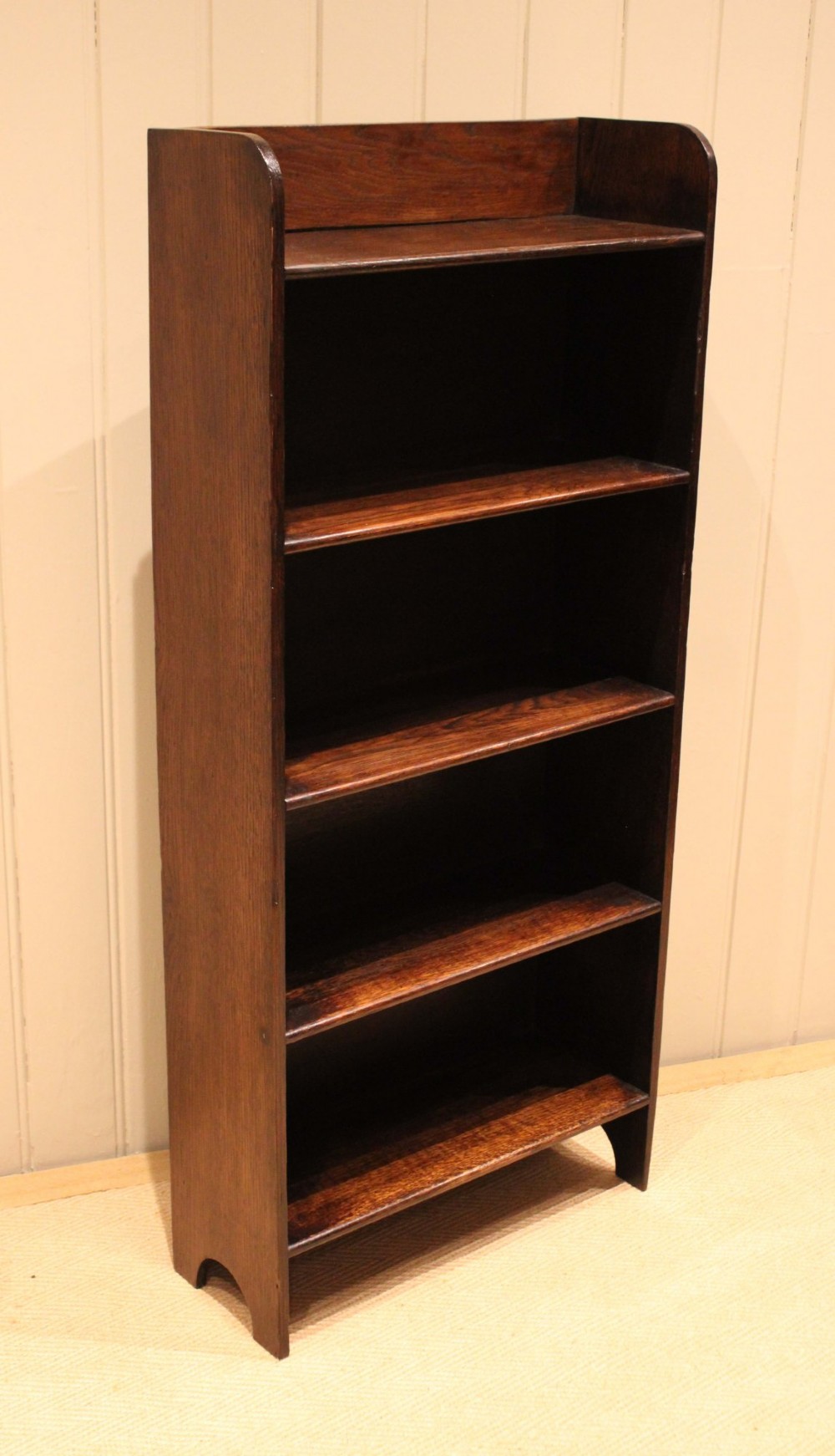 A tall dark oak open bookcase with four fixed shelves and shaped side profile cut-outs at the base. View VIII
