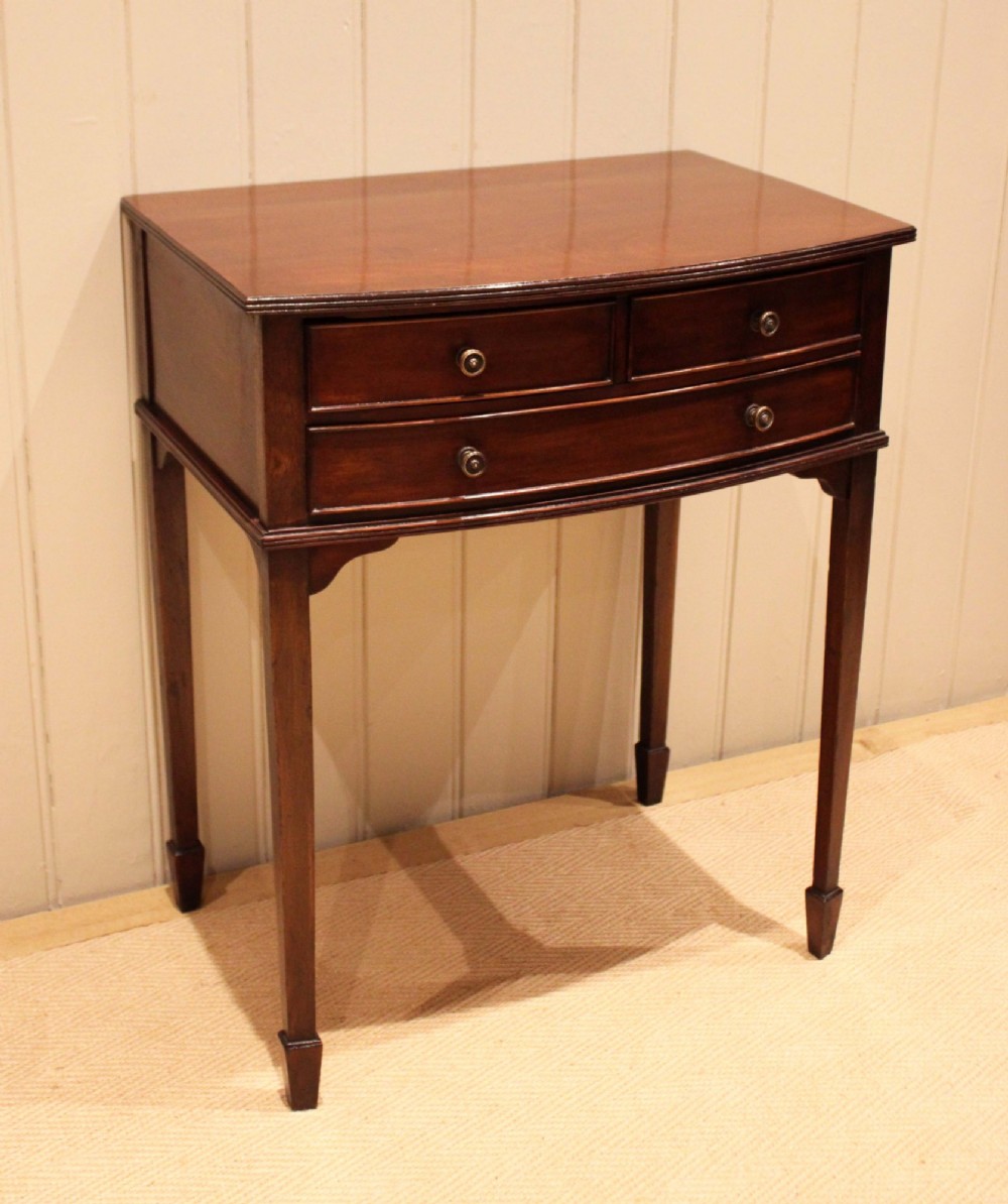 An Edwardian mahogany bow-front side table with drawers and brass handles resting on tapered legs. View II
