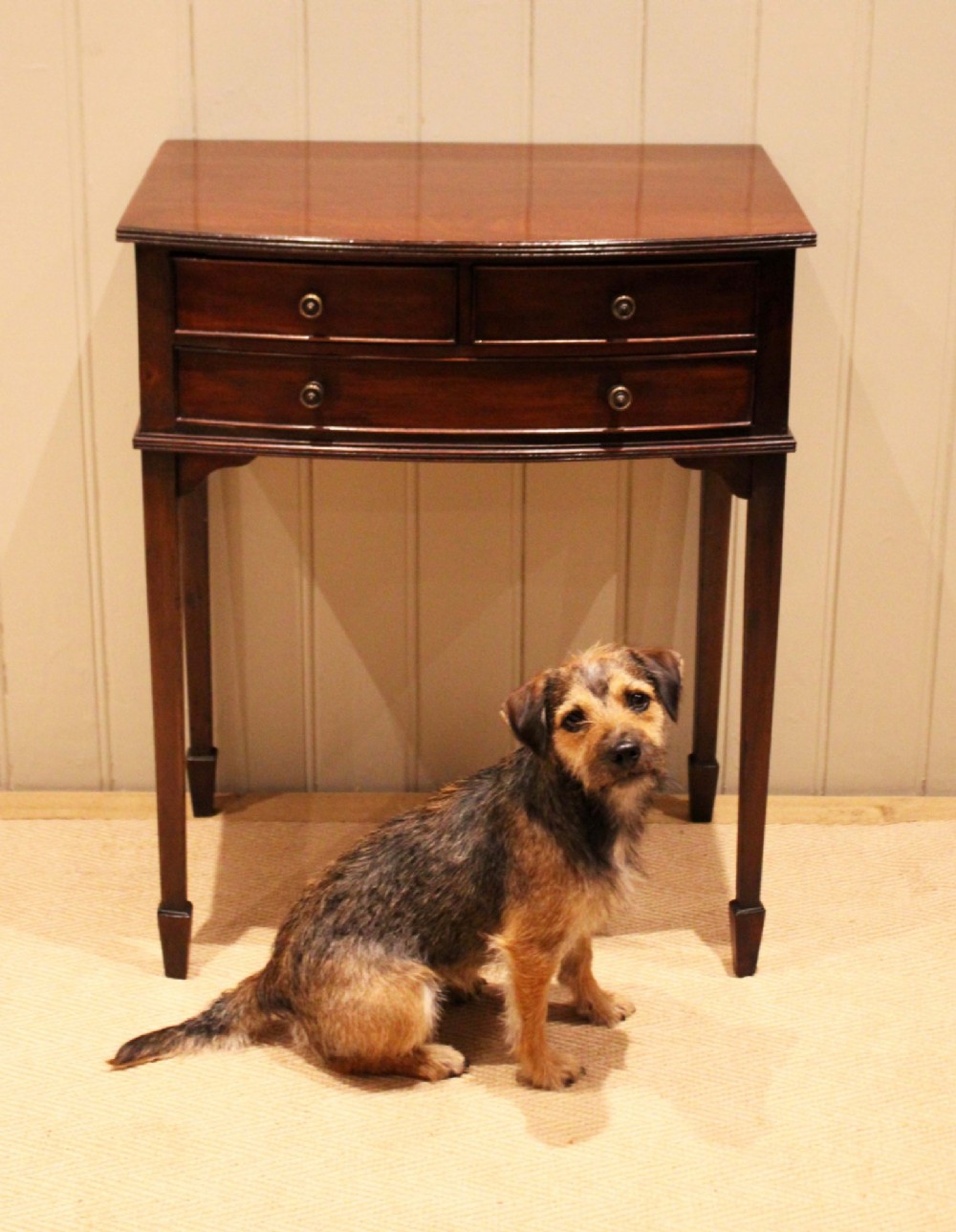 An Edwardian mahogany bow-front side table with drawers and brass handles resting on tapered legs. View IX