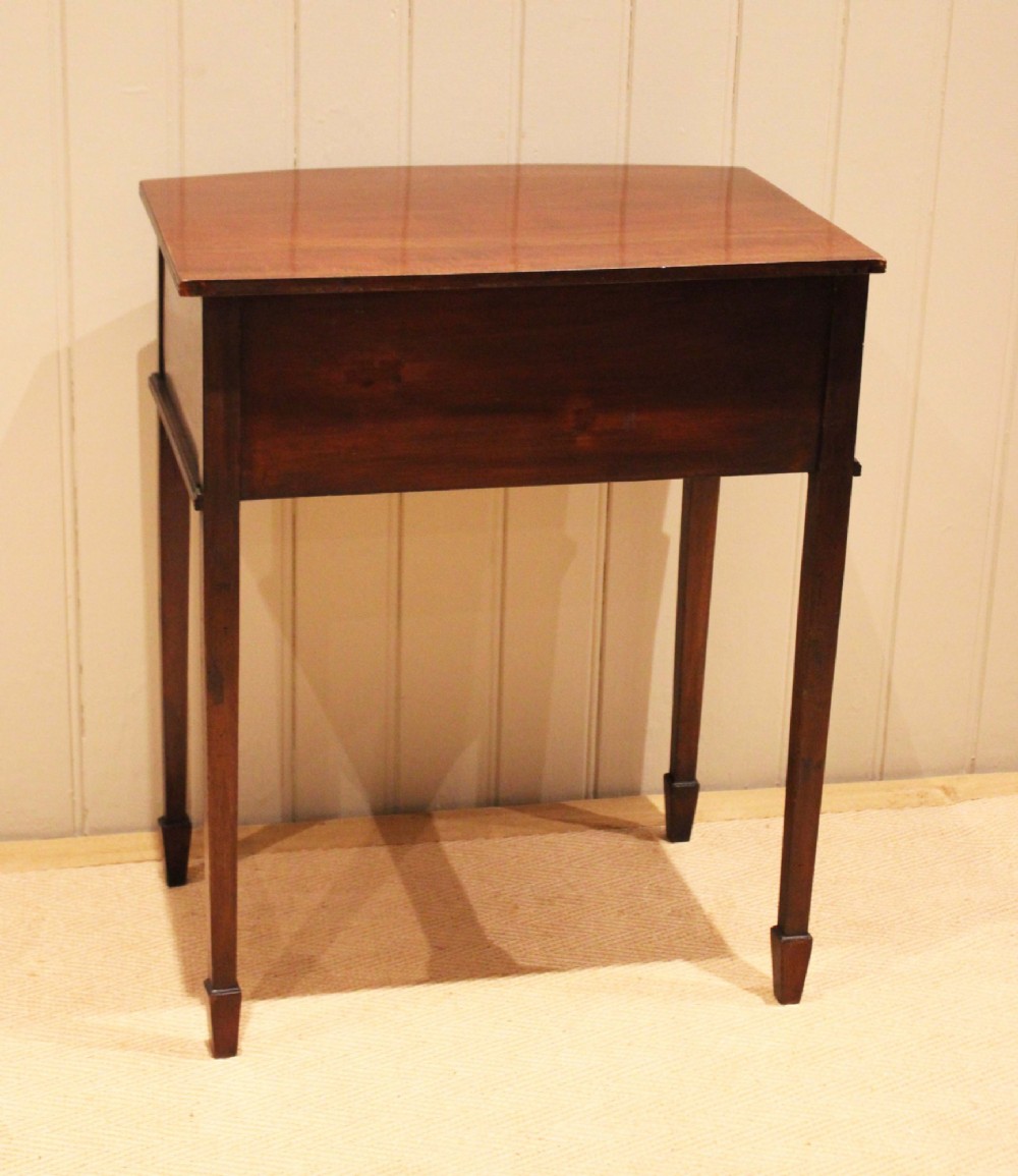An Edwardian mahogany bow-front side table with drawers and brass handles resting on tapered legs. View XII