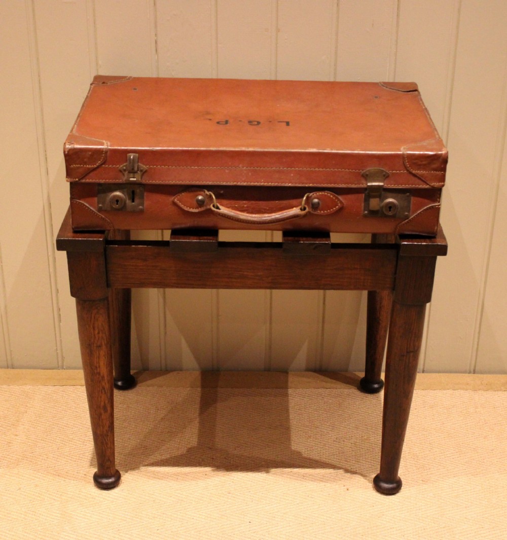 A solid dark oak luggage stand featuring a four-slat top surface supported by four turned tapered legs. View II