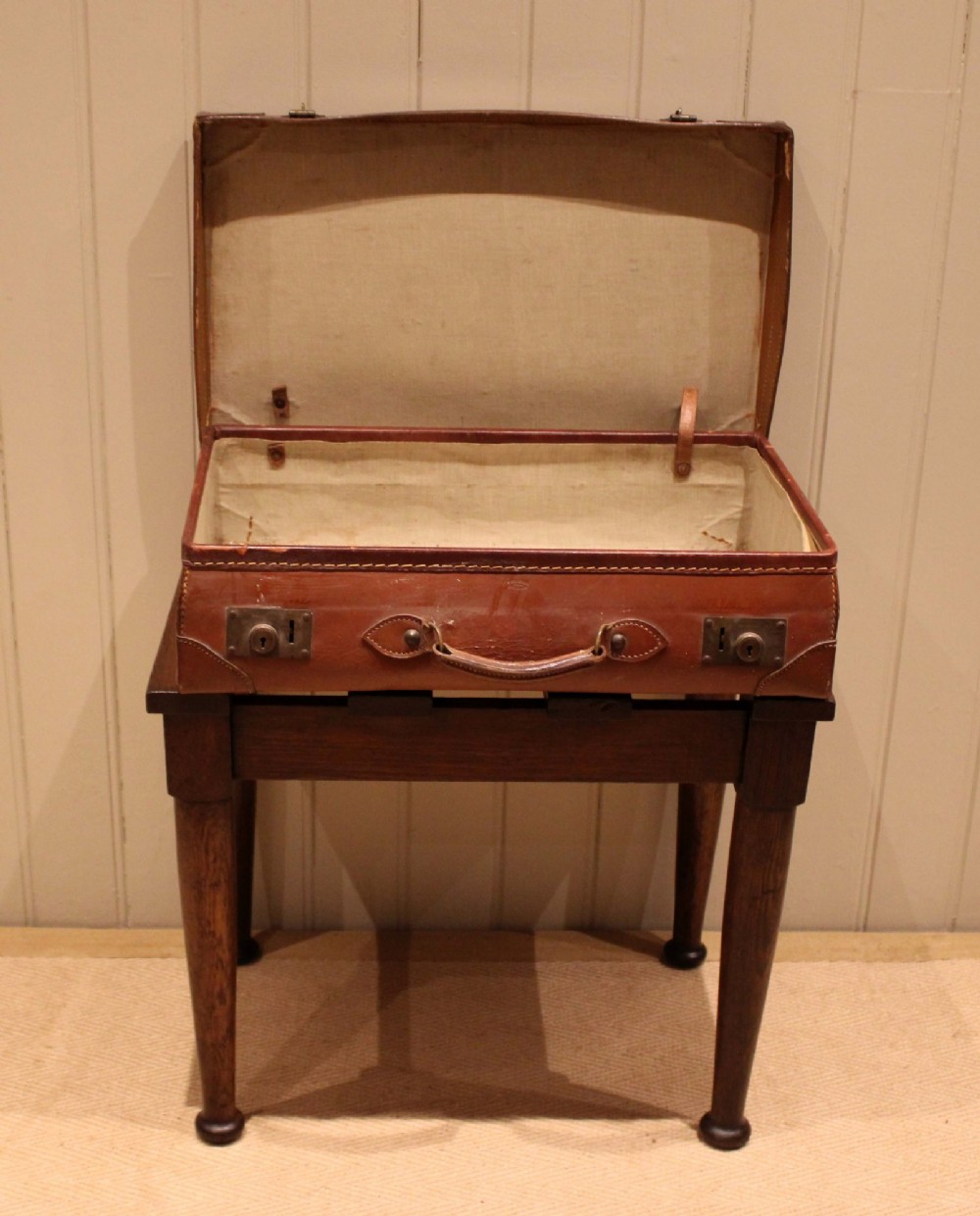 A solid dark oak luggage stand featuring a four-slat top surface supported by four turned tapered legs. View III