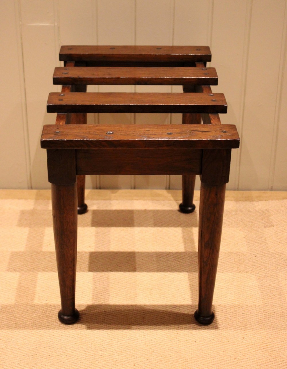 A solid dark oak luggage stand featuring a four-slat top surface supported by four turned tapered legs. View VIII