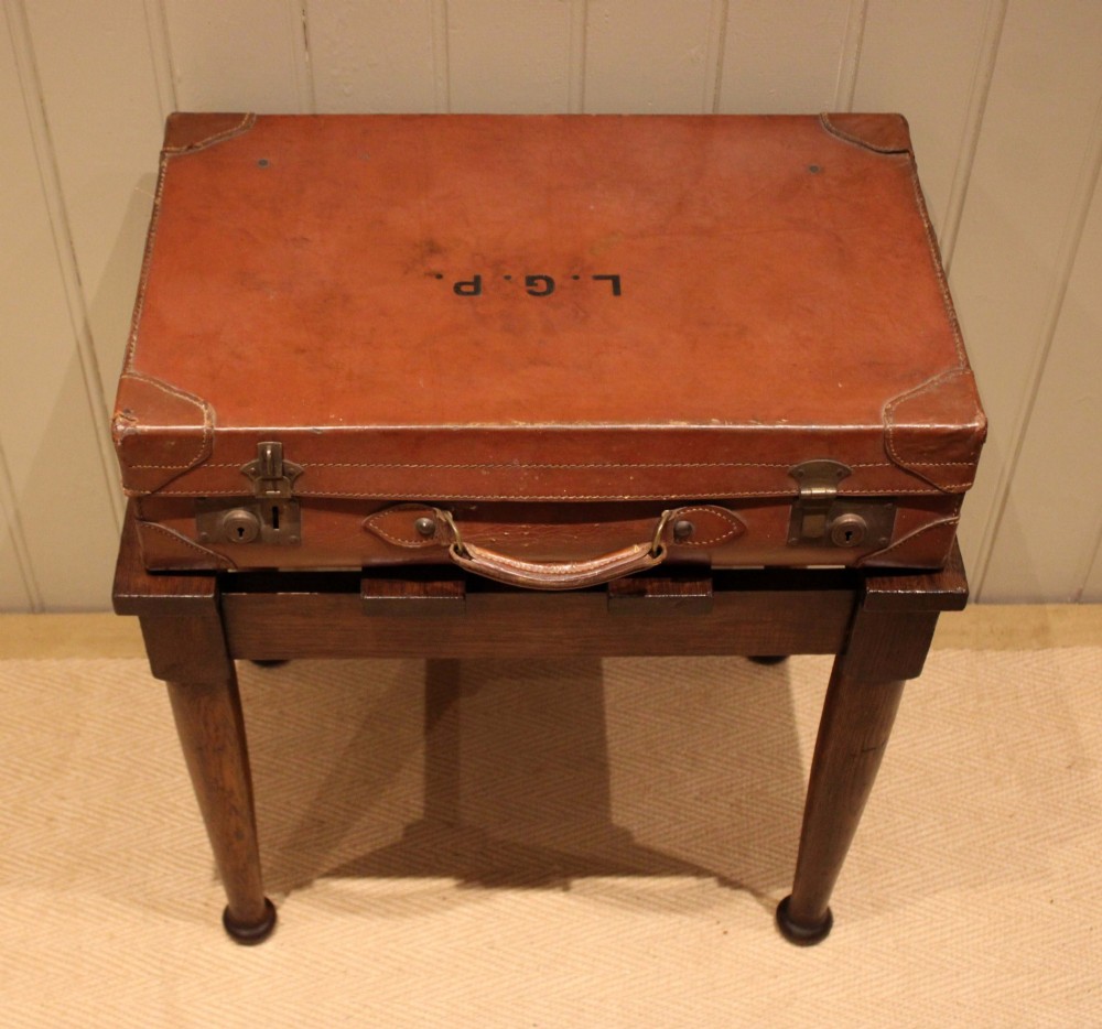 A solid dark oak luggage stand featuring a four-slat top surface supported by four turned tapered legs. View IX