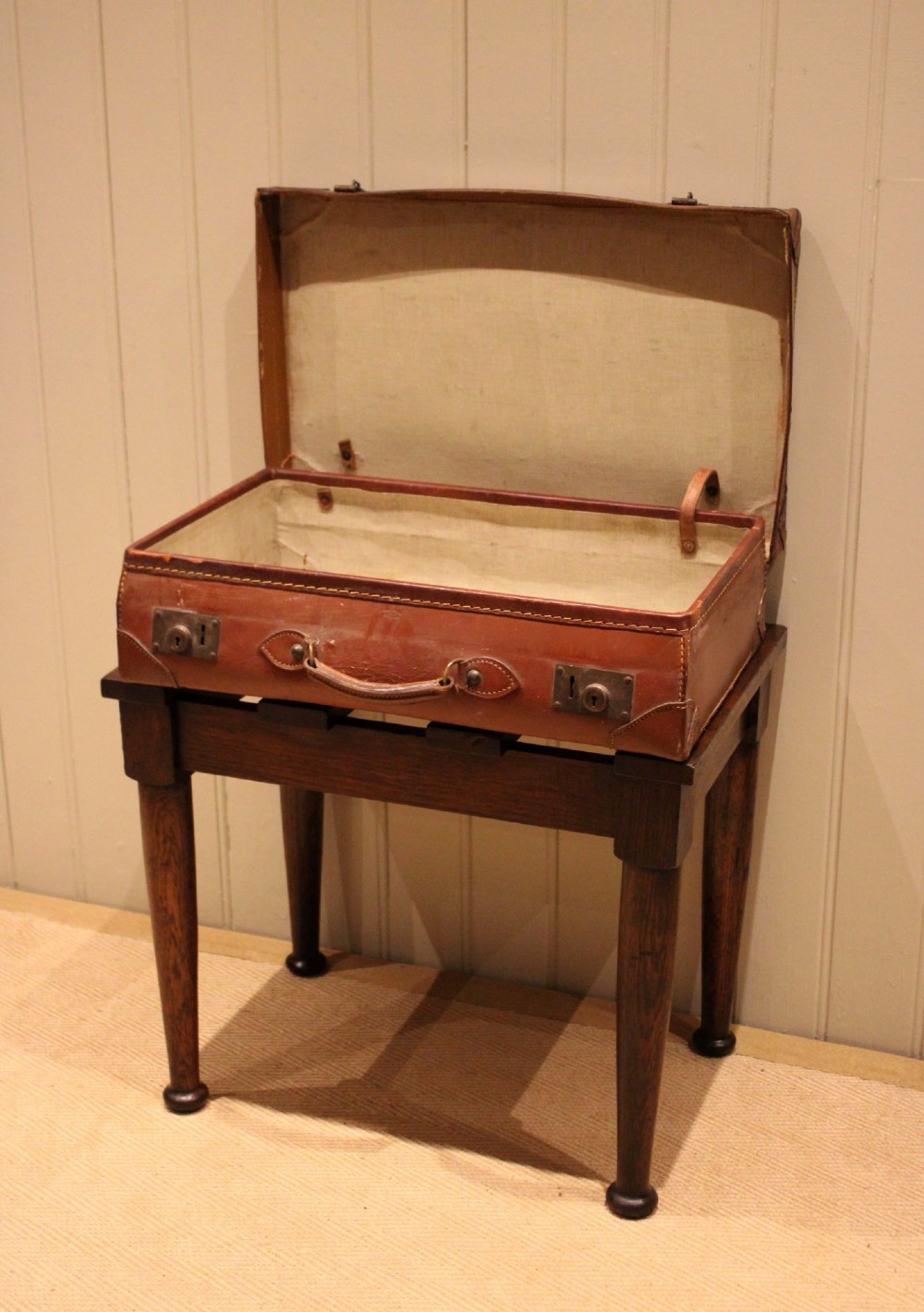 A solid dark oak luggage stand featuring a four-slat top surface supported by four turned tapered legs. View X
