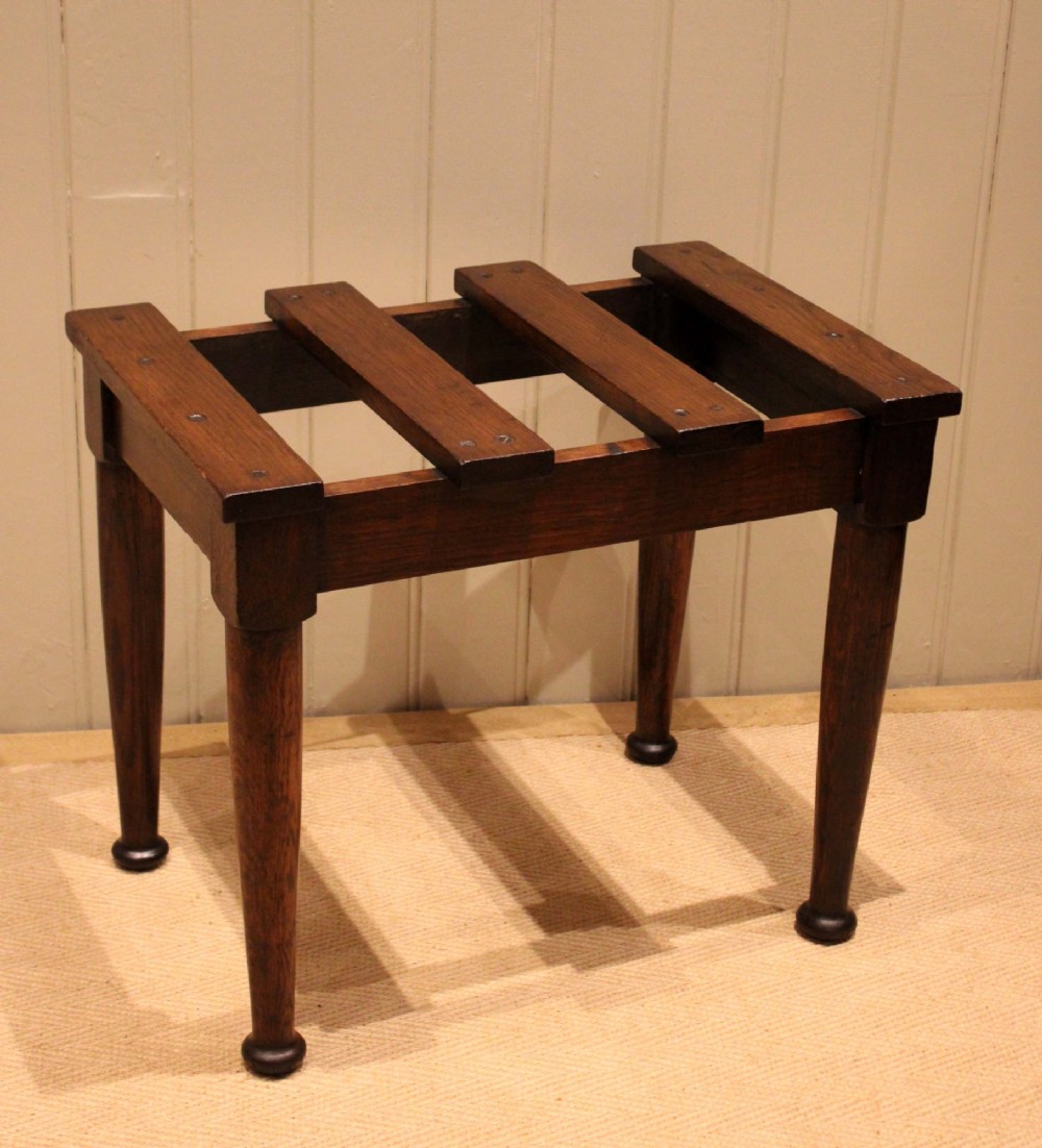 A solid dark oak luggage stand featuring a four-slat top surface supported by four turned tapered legs. View XI