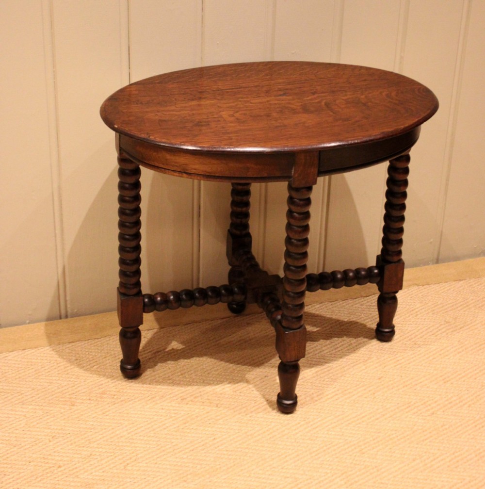 An antique dark oak side table featuring a smooth oval top supported by four bobbin-turned legs and matching low stretchers. View II