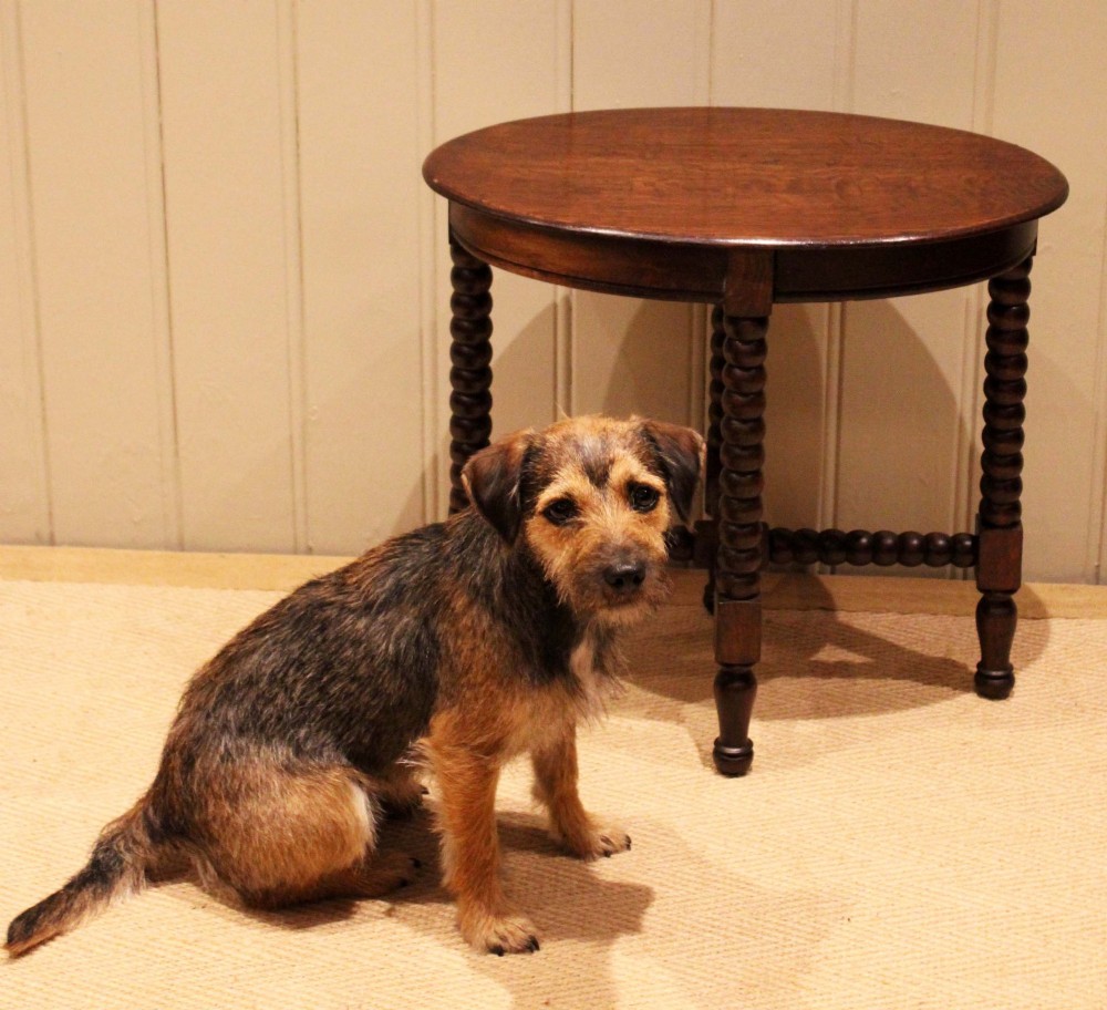 An antique dark oak side table featuring a smooth oval top supported by four bobbin-turned legs and matching low stretchers. View IV