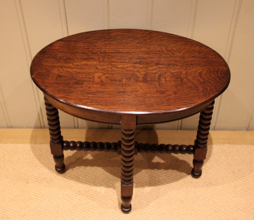 An antique dark oak side table featuring a smooth oval top supported by four bobbin-turned legs and matching low stretchers. View V