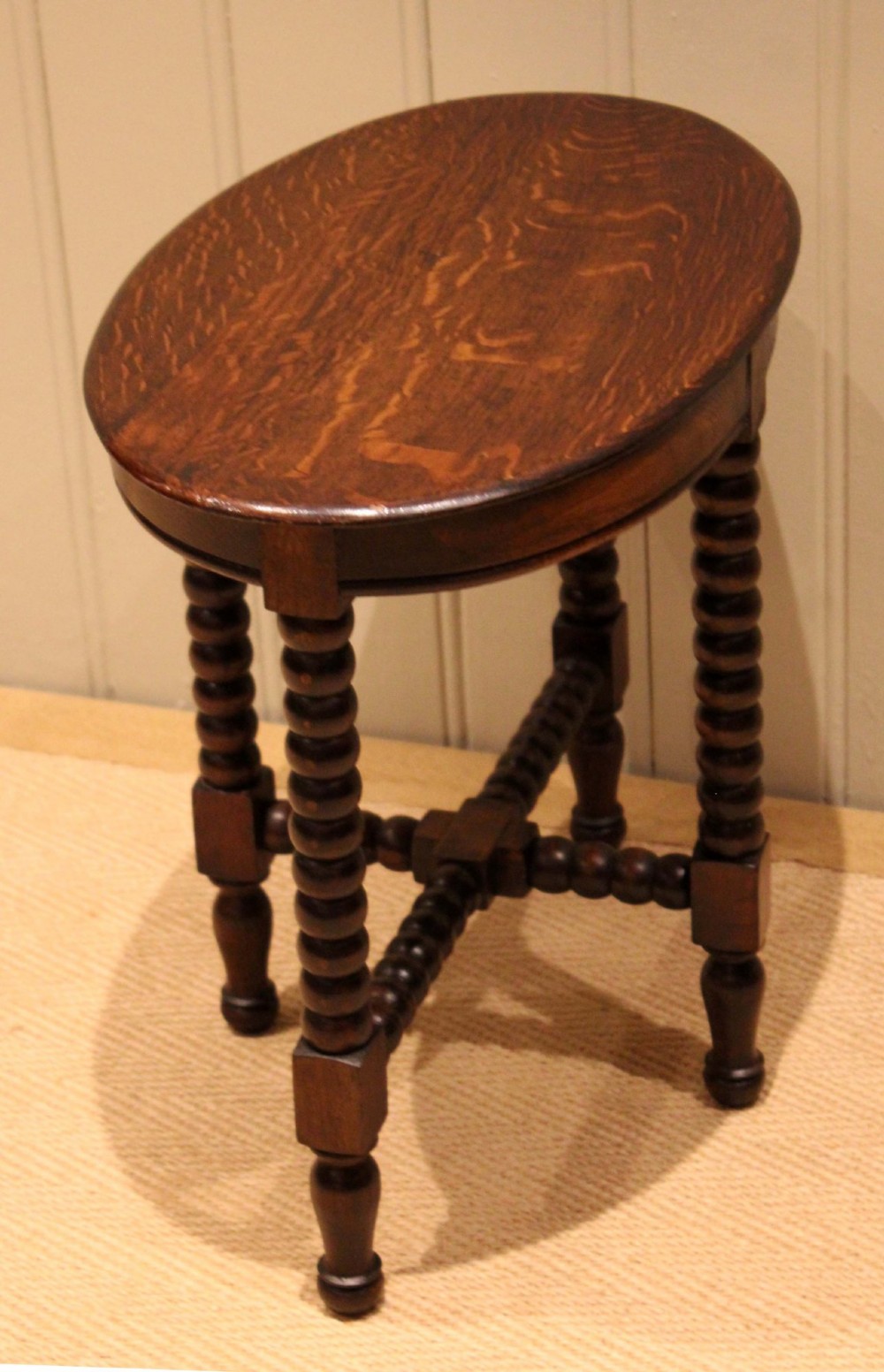 An antique dark oak side table featuring a smooth oval top supported by four bobbin-turned legs and matching low stretchers. View XI