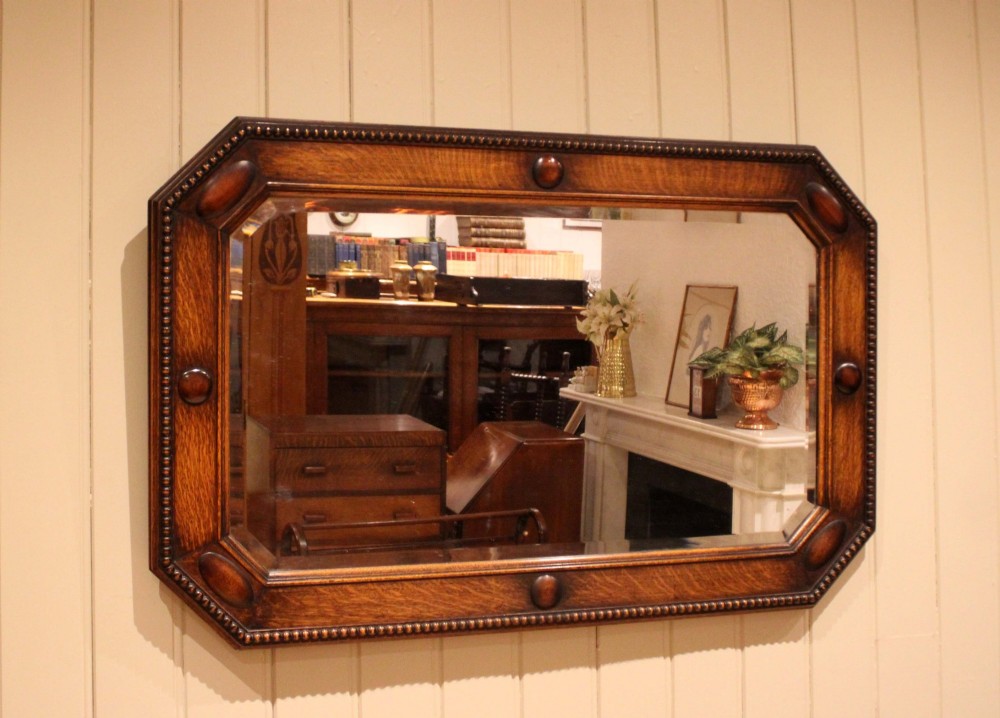A large rectangular oak wall mirror with canted corners, beaded outer moulding, carved oval bosses, and a bevelled glass plate. View III