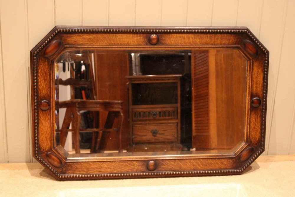 A large rectangular oak wall mirror with canted corners, beaded outer moulding, carved oval bosses, and a bevelled glass plate. View IV