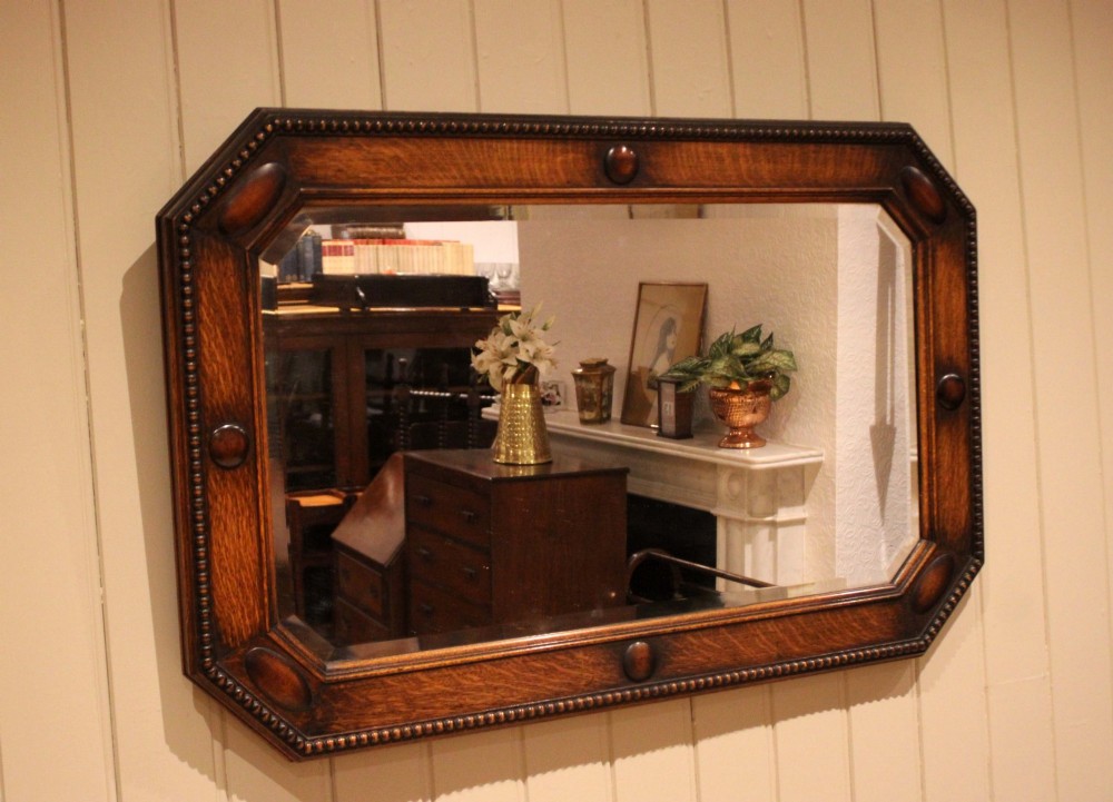 A large rectangular oak wall mirror with canted corners, beaded outer moulding, carved oval bosses, and a bevelled glass plate. View VI