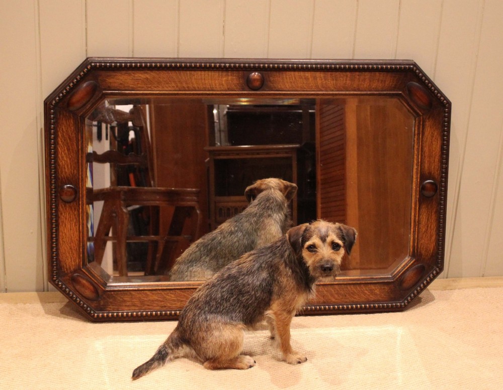 A large rectangular oak wall mirror with canted corners, beaded outer moulding, carved oval bosses, and a bevelled glass plate. View VIII