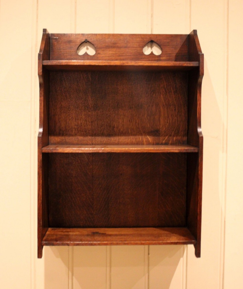 Dark oak Arts and Crafts three-tier wall shelving unit with two pierced heart cut-outs along the upper gallery rail. View II
