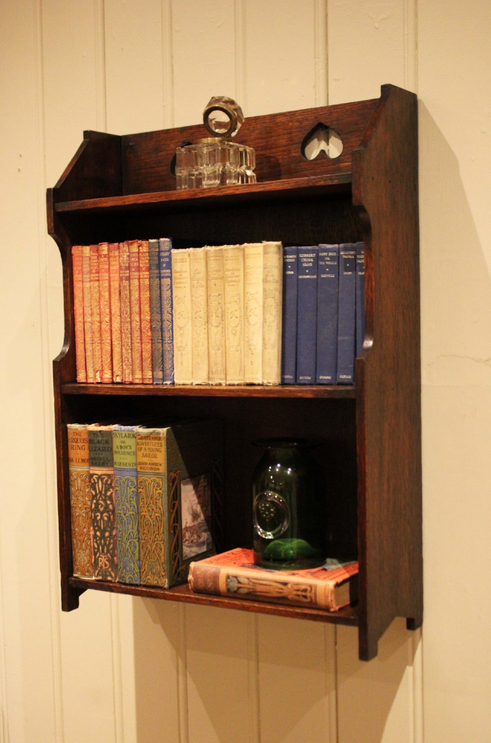 Dark oak Arts and Crafts three-tier wall shelving unit with two pierced heart cut-outs along the upper gallery rail. View III