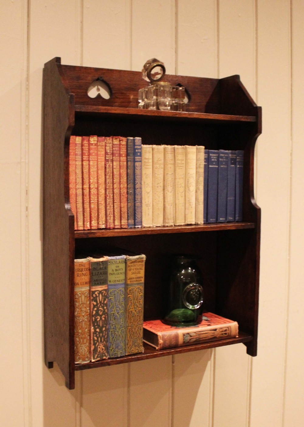 Dark oak Arts and Crafts three-tier wall shelving unit with two pierced heart cut-outs along the upper gallery rail. View V
