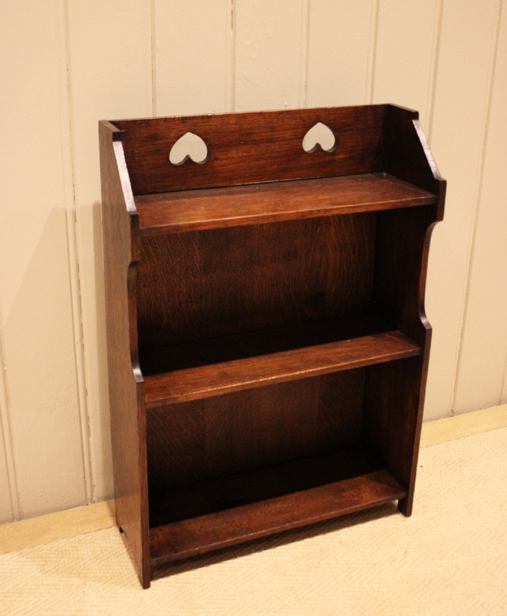 Dark oak Arts and Crafts three-tier wall shelving unit with two pierced heart cut-outs along the upper gallery rail. View XII
