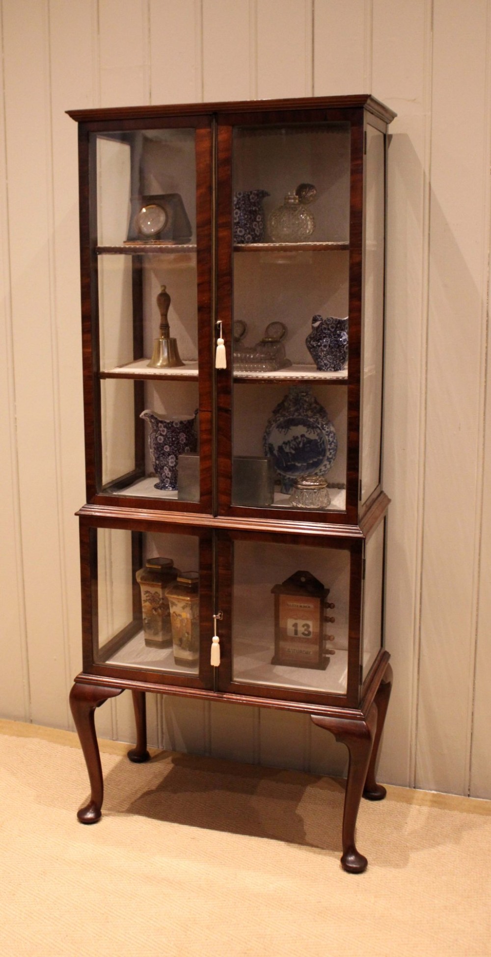 An Edwardian dark mahogany display cabinet with glazed doors and sides, resting on cabriole legs with pad feet. View III