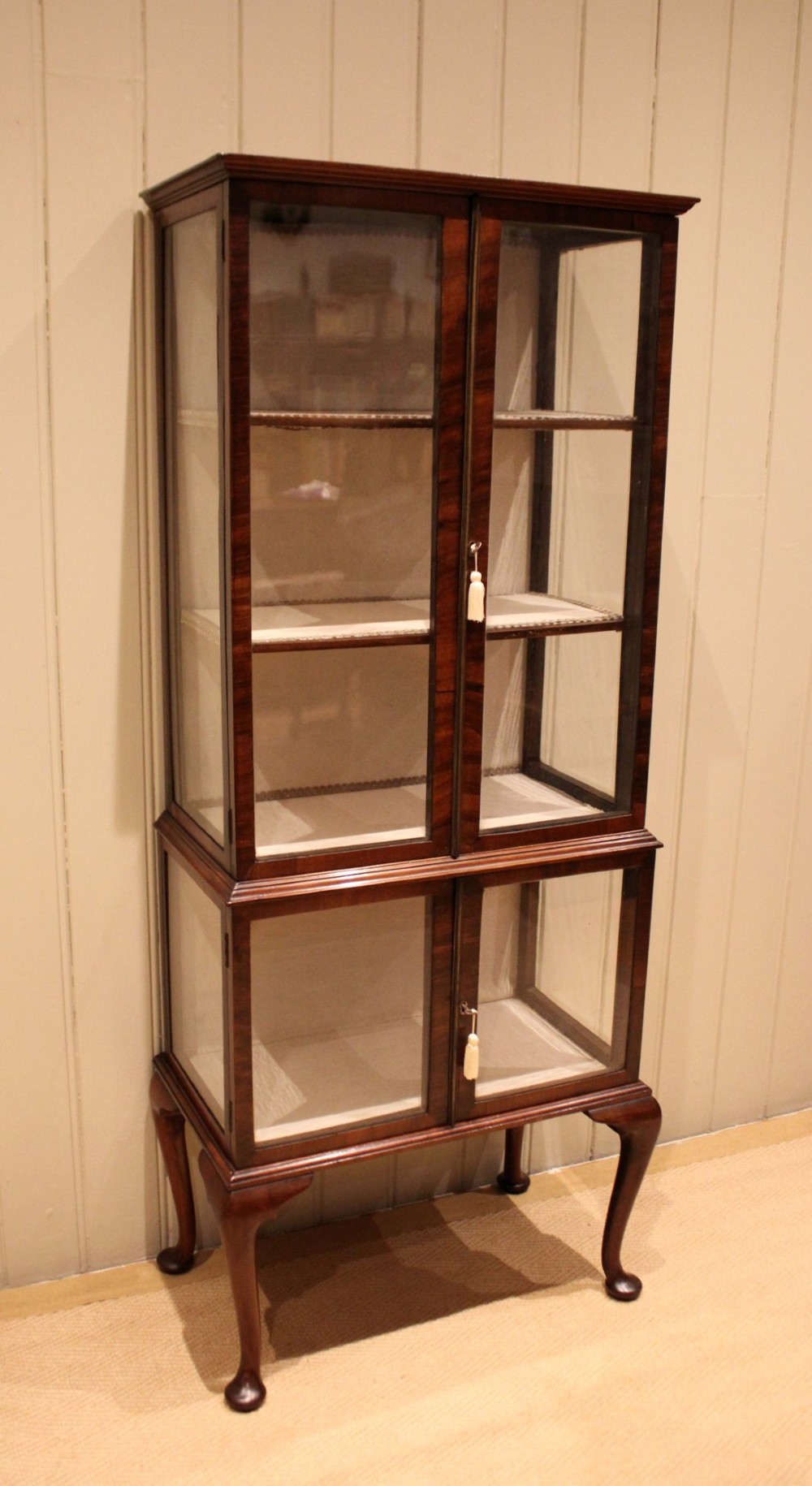 An Edwardian dark mahogany display cabinet with glazed doors and sides, resting on cabriole legs with pad feet. View IV