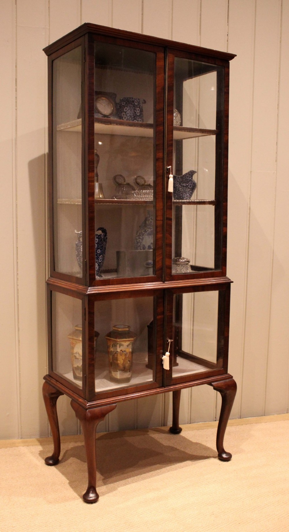 An Edwardian dark mahogany display cabinet with glazed doors and sides, resting on cabriole legs with pad feet. View VII