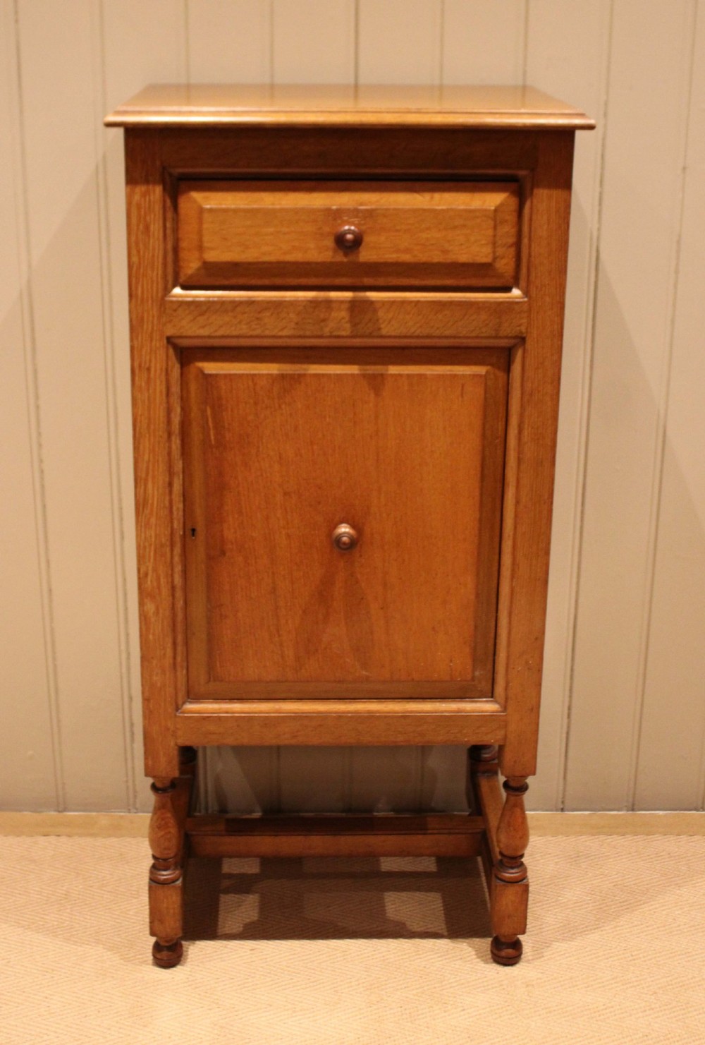 An Edwardian oak side cabinet featuring a single top drawer over a cupboard door with turned wooden knobs and turned legs. View II
