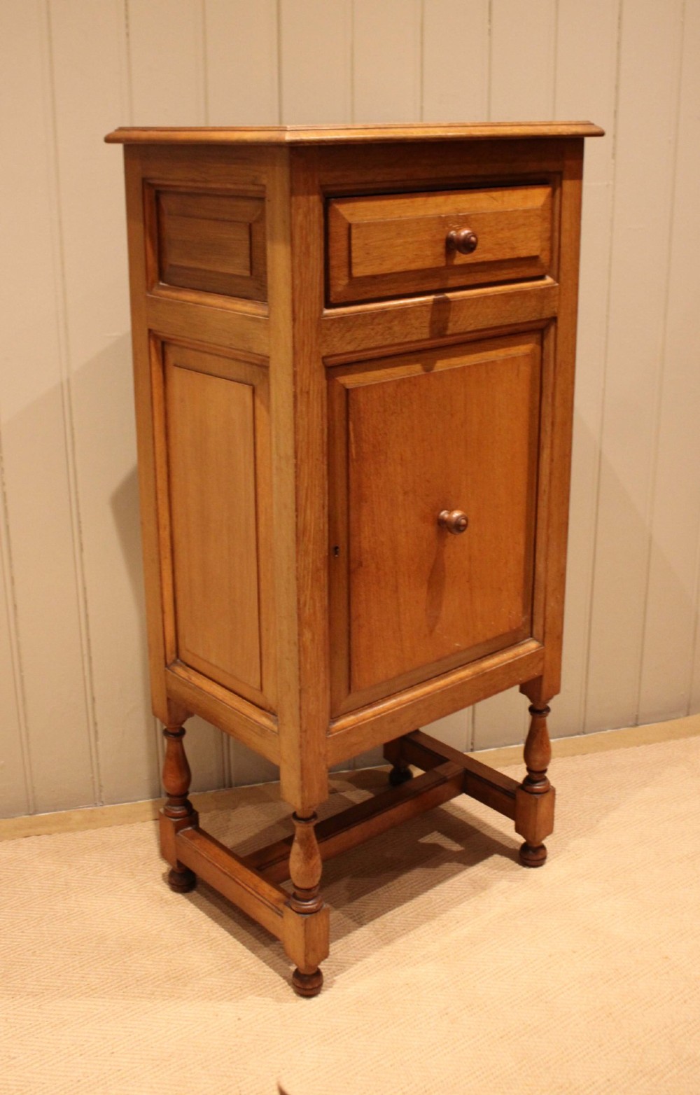 An Edwardian oak side cabinet featuring a single top drawer over a cupboard door with turned wooden knobs and turned legs. View V