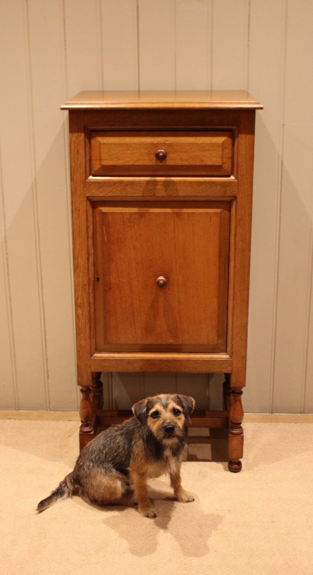 An Edwardian oak side cabinet featuring a single top drawer over a cupboard door with turned wooden knobs and turned legs. View VI