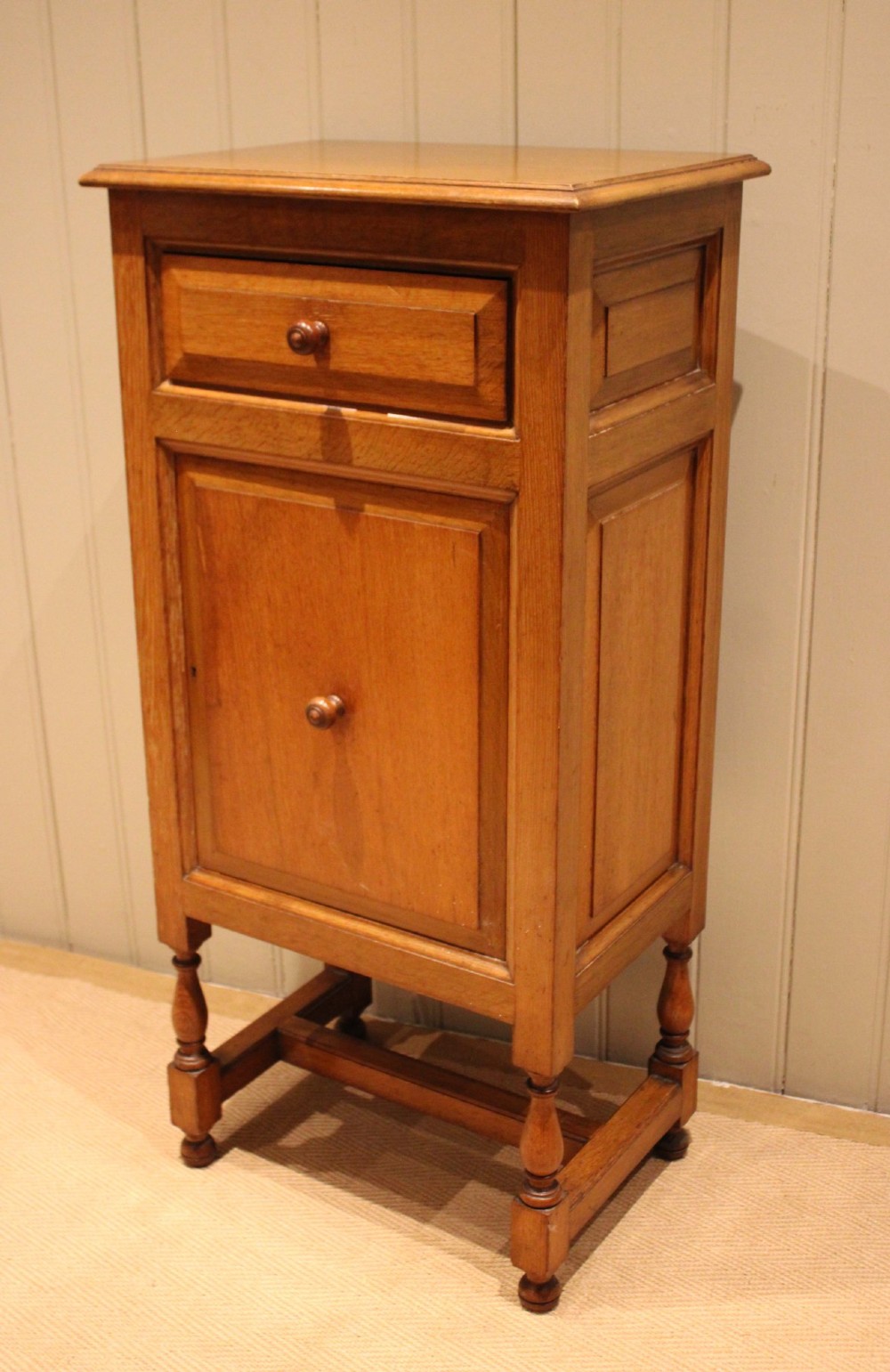 An Edwardian oak side cabinet featuring a single top drawer over a cupboard door with turned wooden knobs and turned legs. View VII