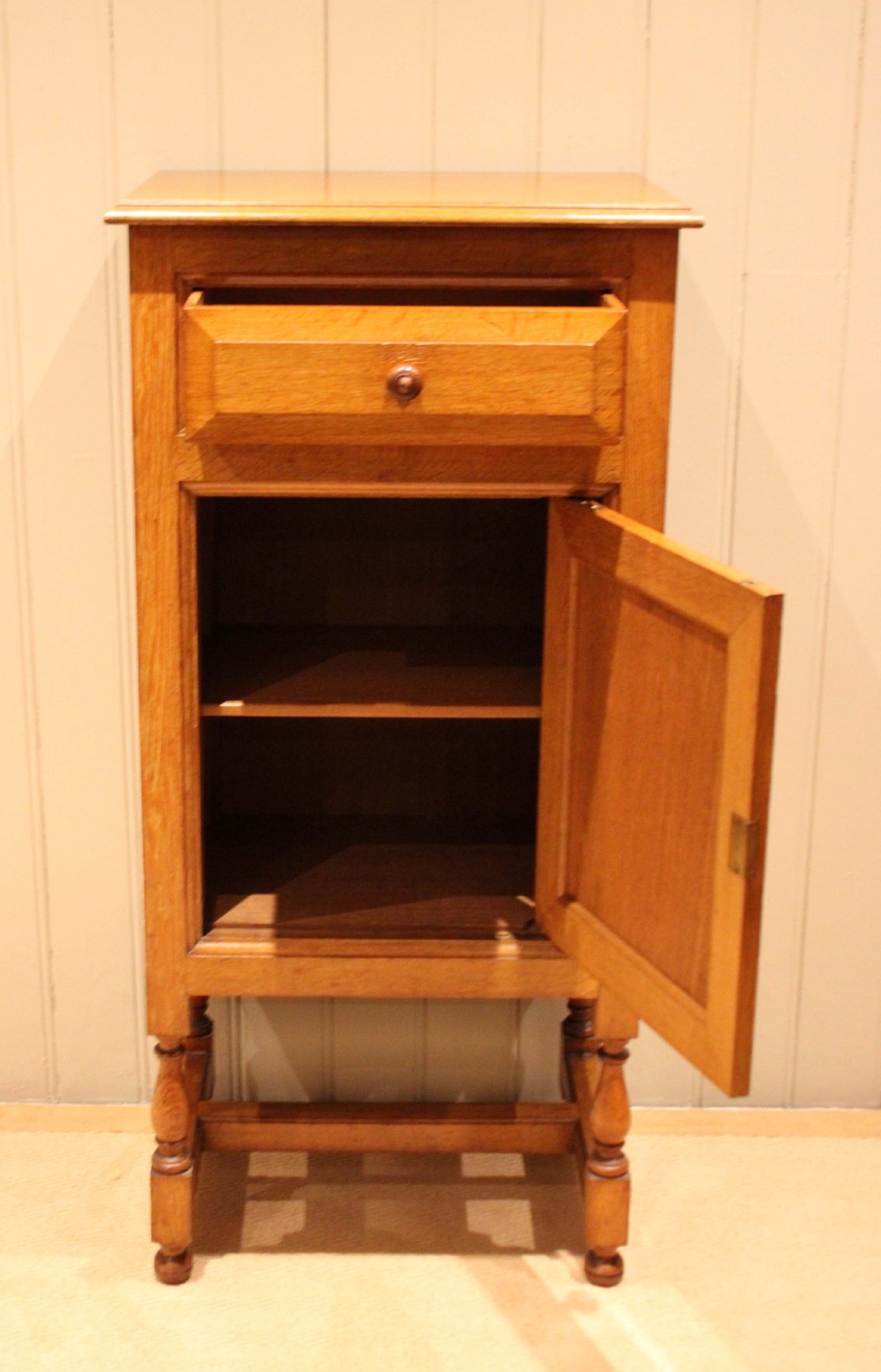 An Edwardian oak side cabinet featuring a single top drawer over a cupboard door with turned wooden knobs and turned legs. View VIII