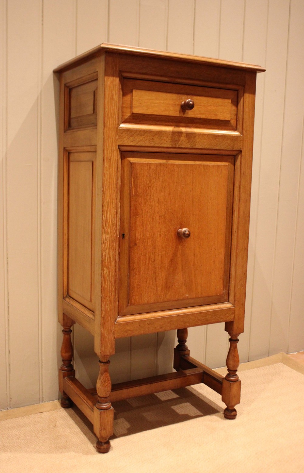 An Edwardian oak side cabinet featuring a single top drawer over a cupboard door with turned wooden knobs and turned legs. View X