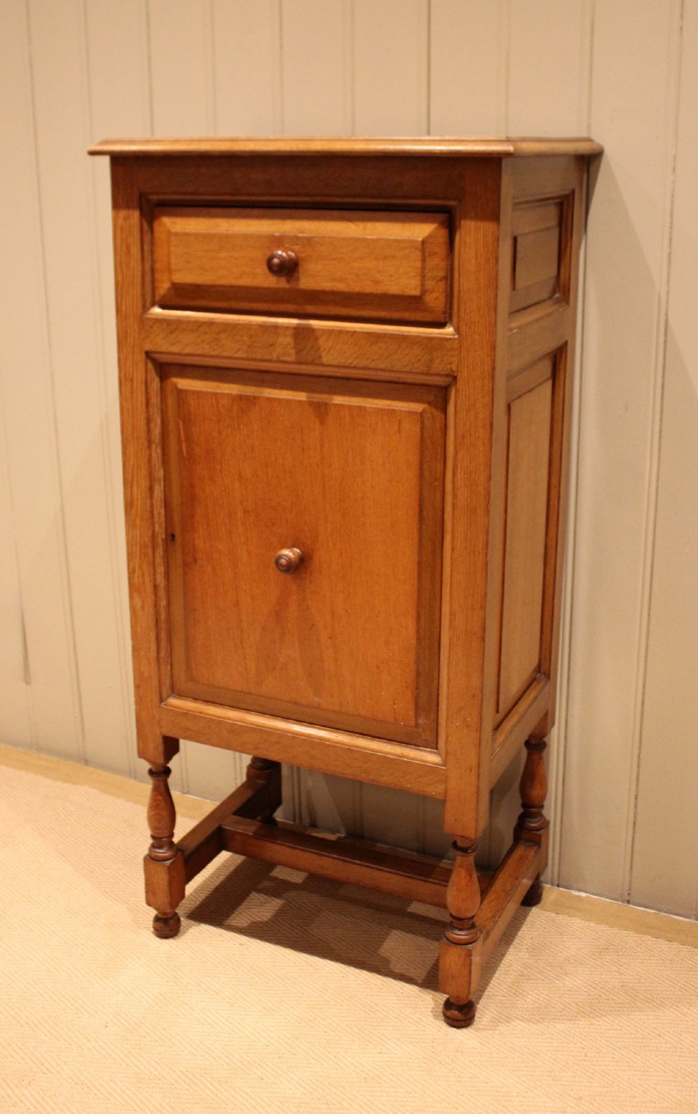 An Edwardian oak side cabinet featuring a single top drawer over a cupboard door with turned wooden knobs and turned legs. View XI