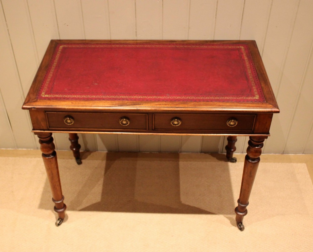 A late 19th-century mahogany writing desk featuring a red gold-tooled leather writing surface, two drawers with brass ring handles, and turned legs on brass castors. View VIII