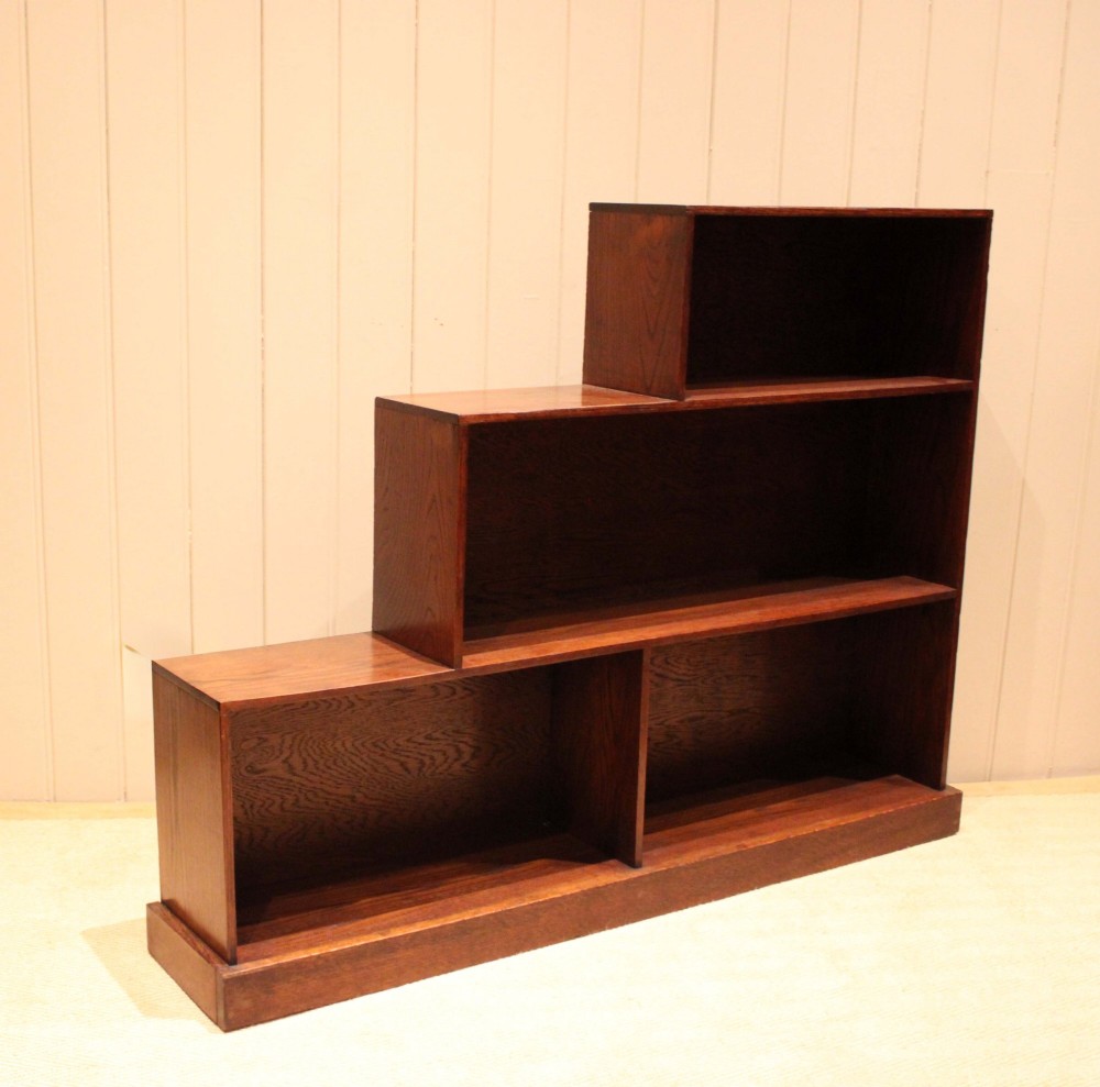 A stepped medium brown oak sectional bookcase with three open tiered shelves arranged in an asymmetrical stair-like configuration. View VIII