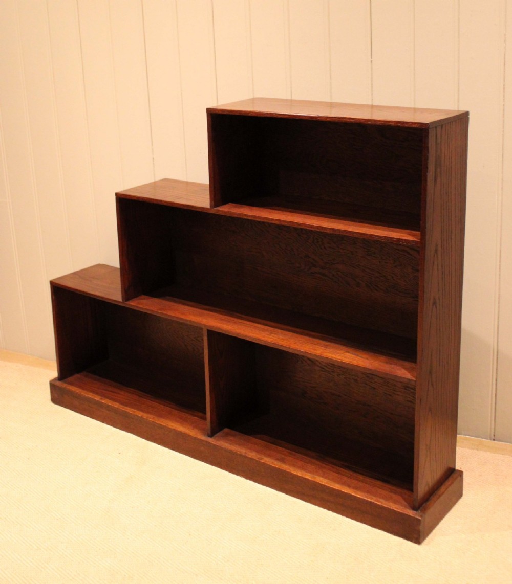 A stepped medium brown oak sectional bookcase with three open tiered shelves arranged in an asymmetrical stair-like configuration. View X