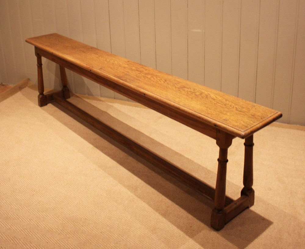 A long rectangular solid oak bench featuring turned legs connected by a low stretcher rail. View III
