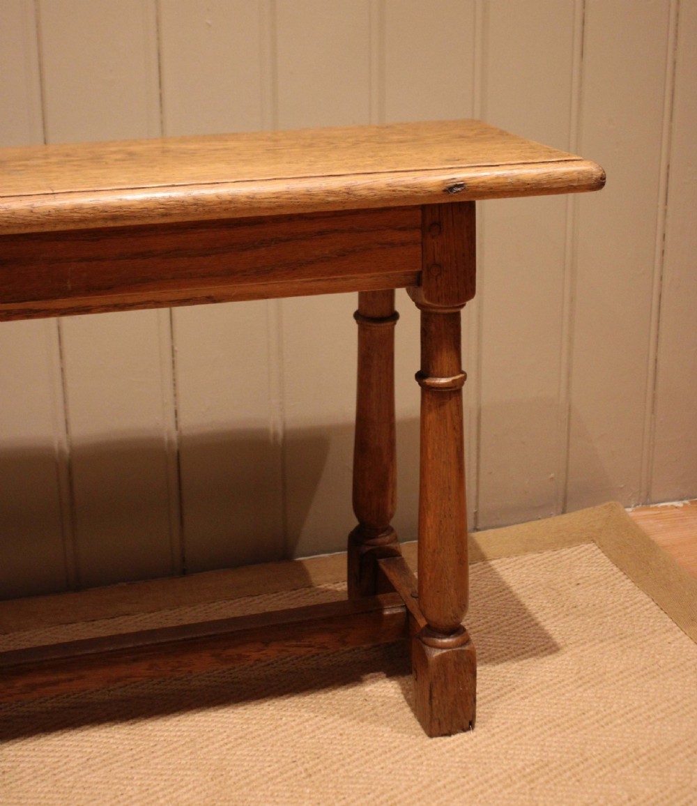 A long rectangular solid oak bench featuring turned legs connected by a low stretcher rail. View V