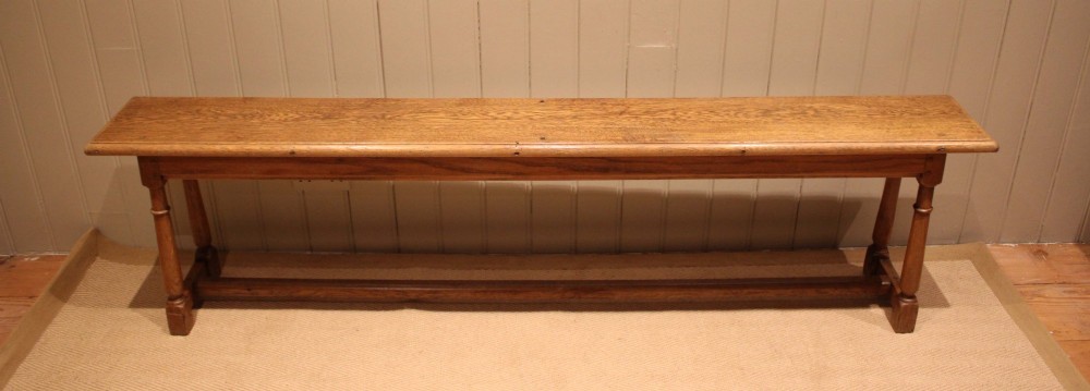 A long rectangular solid oak bench featuring turned legs connected by a low stretcher rail. View VIII