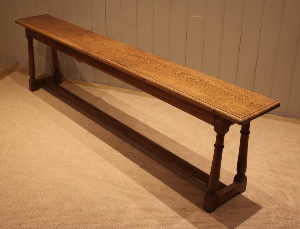 A long rectangular solid oak bench featuring turned legs connected by a low stretcher rail. View IX