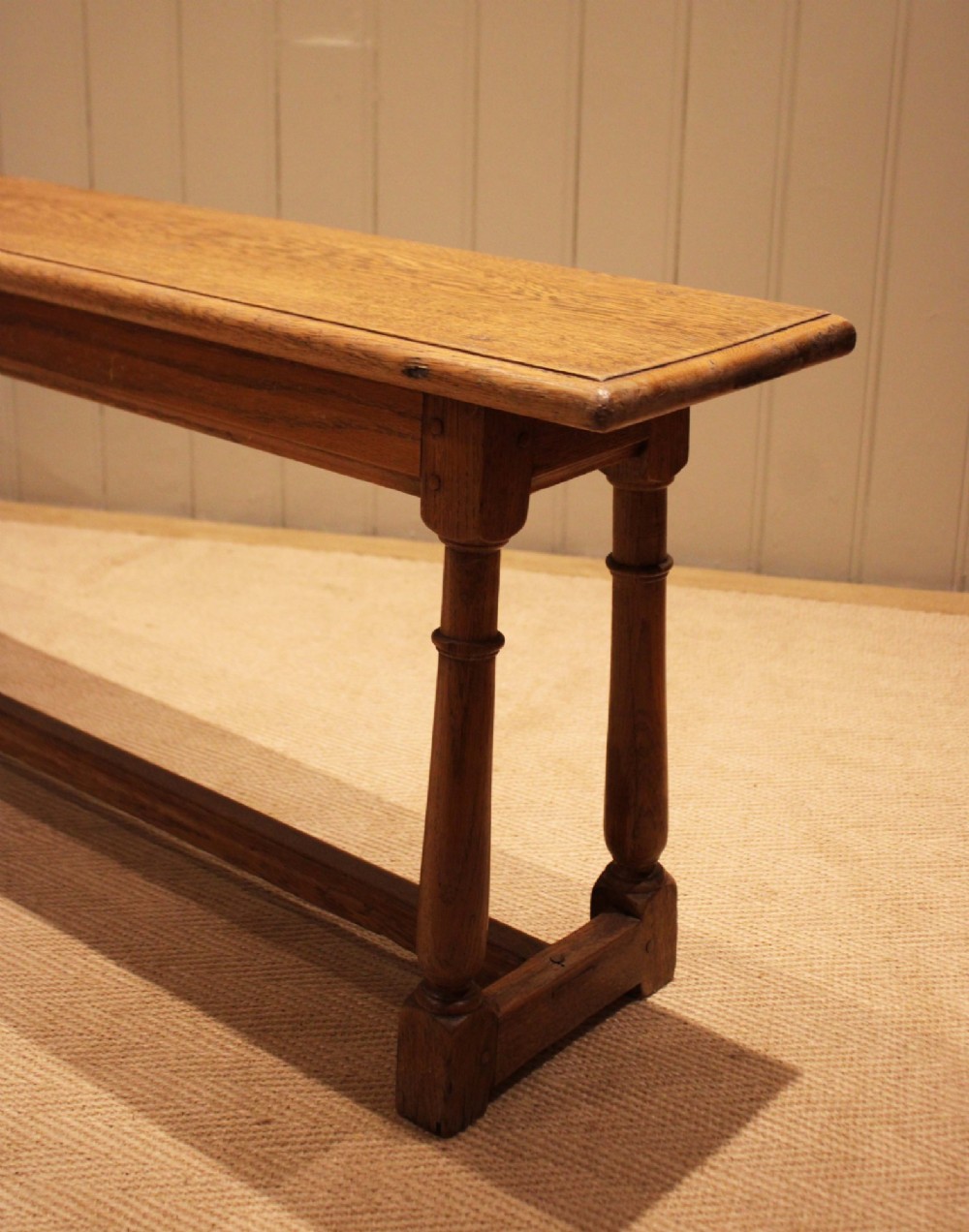 A long rectangular solid oak bench featuring turned legs connected by a low stretcher rail. View X