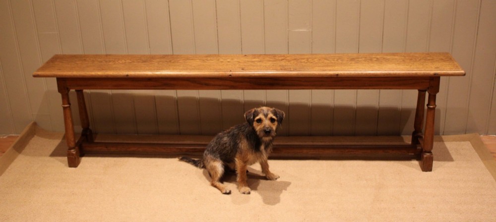 A long rectangular solid oak bench featuring turned legs connected by a low stretcher rail. View XI